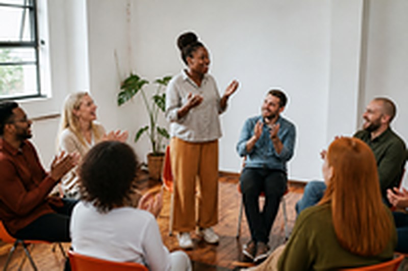 A group cheering as a woman speaks in the hot seat